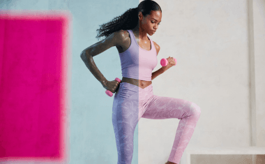 Vrouw in sportkleding doet een oefening met roze gewichten
